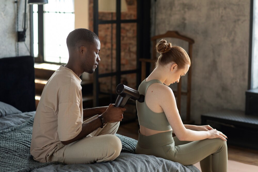 Man using massage gun on woman side view